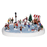 Lemax patinoire vue face avec stand chocolat et patineurs animés pour ambiance festive