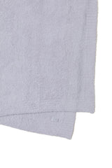 Barefoot Dreams plaid plié sur lit offrant confort esthétique et gain de place