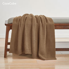 CozeCube plaid plié dans un panier, facile à ranger et inviter au cocooning