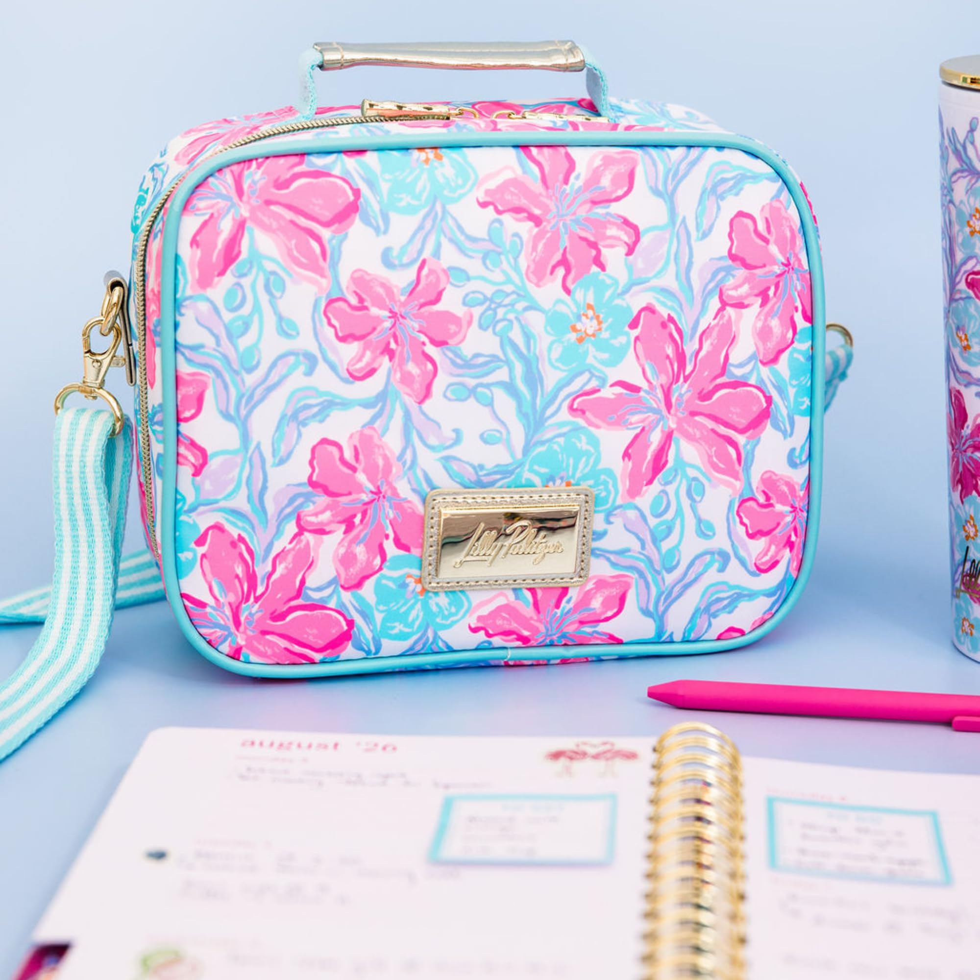 Lilly Pulitzer lunch box posée à la plage pour un pique-nique stylé