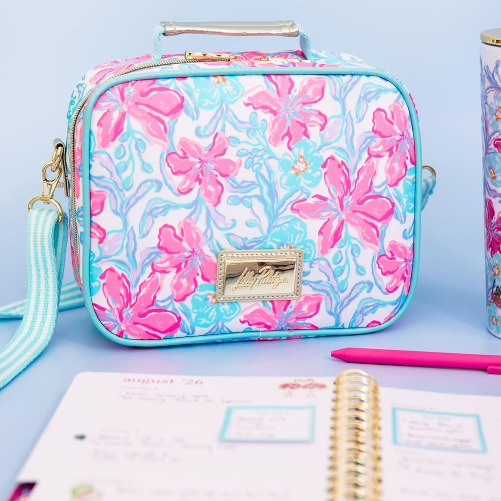 Lilly Pulitzer lunch box posée à la plage pour un pique-nique stylé