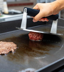 Manucode presse en usage sur poêle écrasant un burger pour croûte
