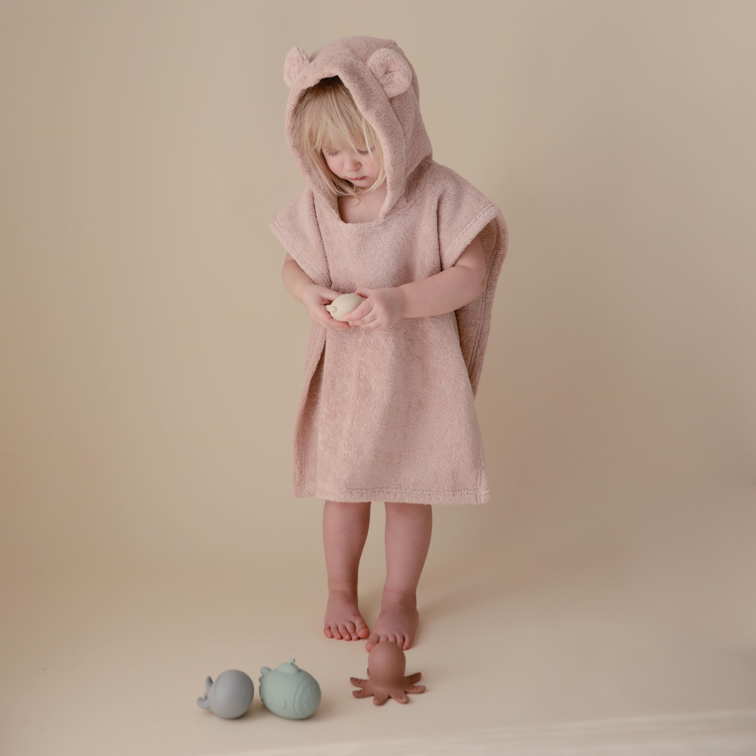 mushie poncho plié avec échelle de taille pour comparaison pratique