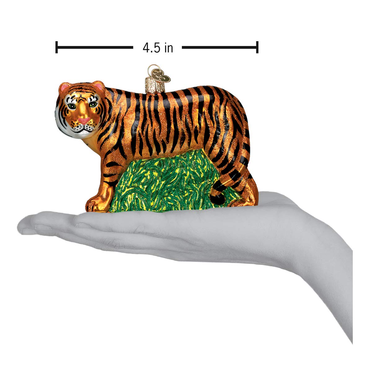 Old World Christmas tigre posé à côté d'une main pour échelle pratique