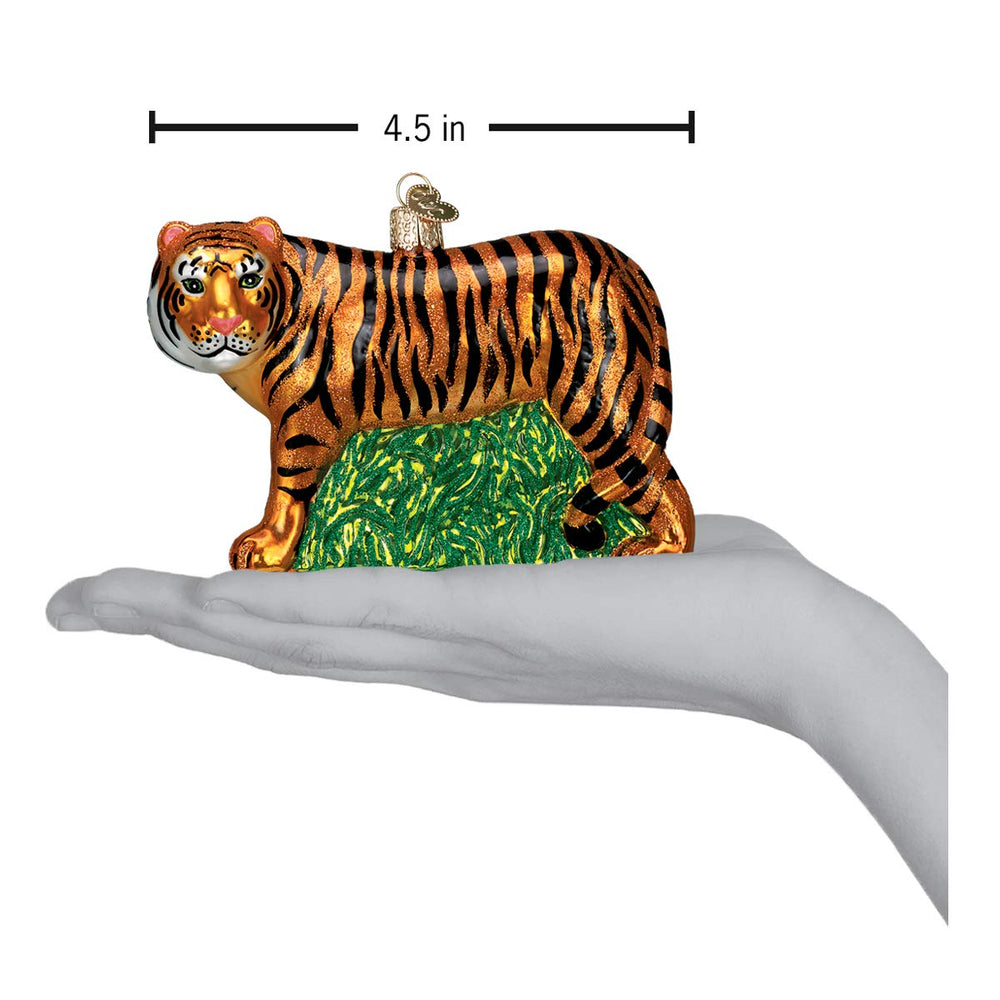 Old World Christmas tigre posé à côté d'une main pour échelle pratique