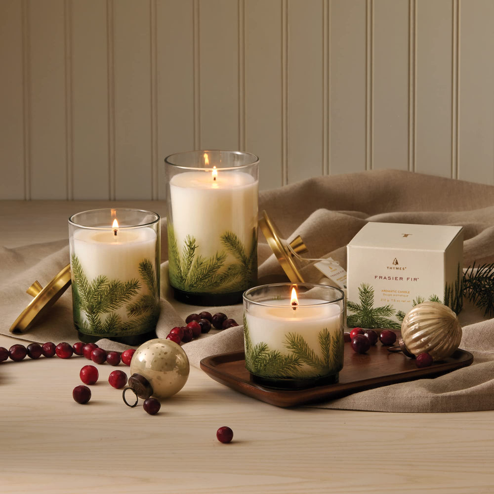 Bougie Thymes Frasier Fir posée sur une table de Noël créant une ambiance chaleureuse
