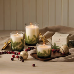 Bougie Thymes Frasier Fir posée sur une table de Noël créant une ambiance chaleureuse