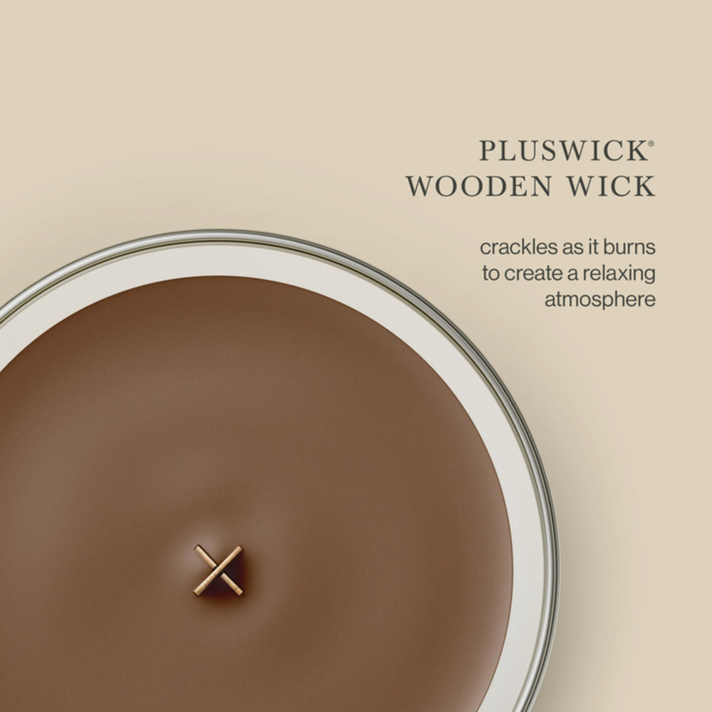 WoodWick bougie allumée près d'une cheminée créant atmosphère cosy